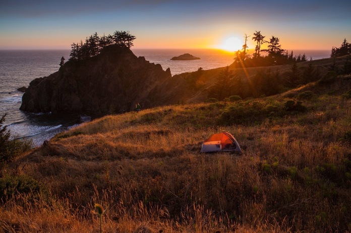 The sun sets on the Pacific and a tent campsite with beautiful displays of color